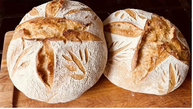 Two loaves of home-baked sourdough bread, hand-scored